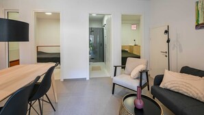 Un salon moderne comprenant un coin repas, un canapé, un fauteuil et une petite table.