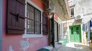 Une ruelle étroite avec un bâtiment rose, une porte verte et un petit banc.