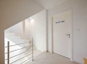 Stairs lead to the upper level, with the BLUE ONE door offering a simple, functional space.