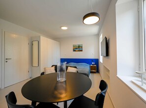 Cozy retreat with a single bed, flat-screen TV, and round dining table for four.
