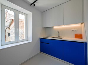 Enjoy a functional kitchen with a sink, modern cabinets, and a window offering a view of the adjacent building.