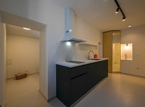 Kitchen features a stove, sink, and stainless steel range hood.