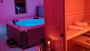 Ein Wellnessraum mit Whirlpool, einer Holzbank und einem Spiegel an der Wand.