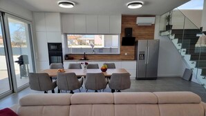 Eine moderne Küche mit Essbereich, einer Couch und einer Treppe.