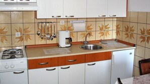 A compact kitchen with white cabinets, a gas stove, a coffee maker, and a sink. - Sweet and Simple Sea view Crikvenica Apartments - One Bedroom Apartment withe Sea view and Balcony (Crikvenica)