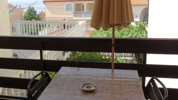 A balcony with a table and chairs, a metal bowl, and a yellow umbrella. - Sweet and Simple Sea view Crikvenica Apartments - One Bedroom Apartment withe Sea view and Balcony (Crikvenica)