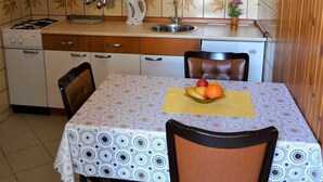 A compact kitchen with a gas stove, a sink, and a dining table set with a fruit basket. - Sweet and Simple Sea view Crikvenica Apartments - One Bedroom Apartment withe Sea view and Balcony (Crikvenica)