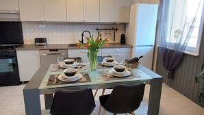 Eine moderne Küche mit weißen Schränken, einem für zwei Personen gedecktem Esstisch und einer Vase mit Tulpen.