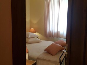 A bedroom with a bed, pillows, a nightstand, a lamp, and a window with curtains. - Superior one bedroom apartment (Marcana)