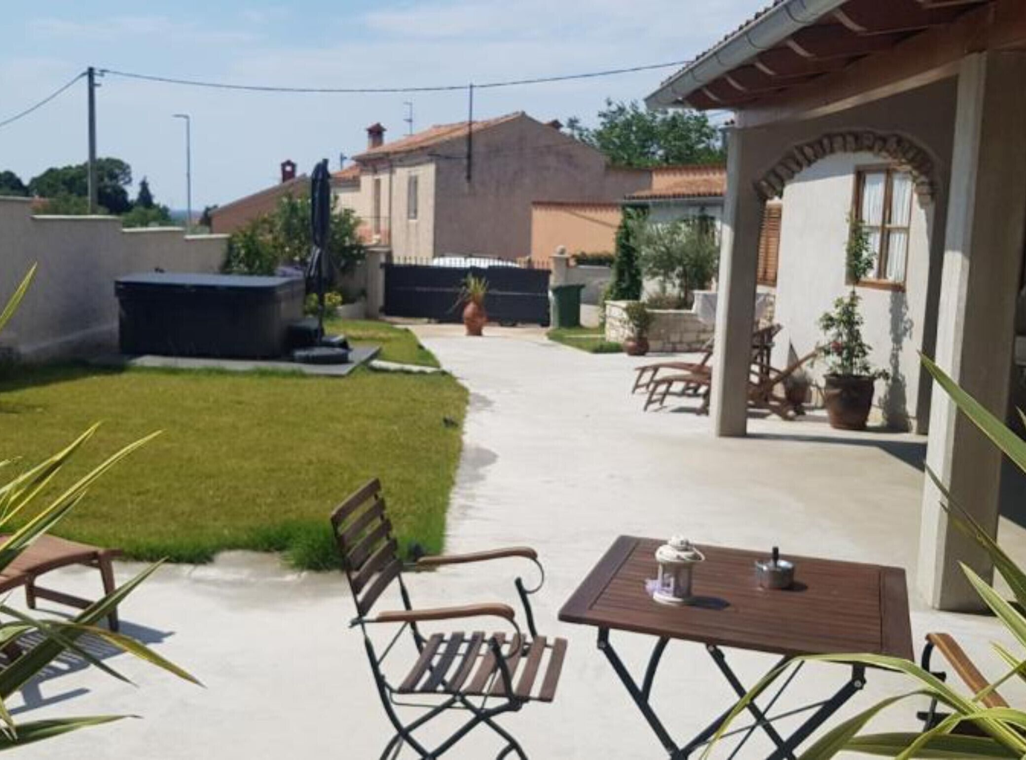 Eine Terrasse mit Tisch und Stühlen, ein kleiner Garten und ein Gebäude im Hintergrund.