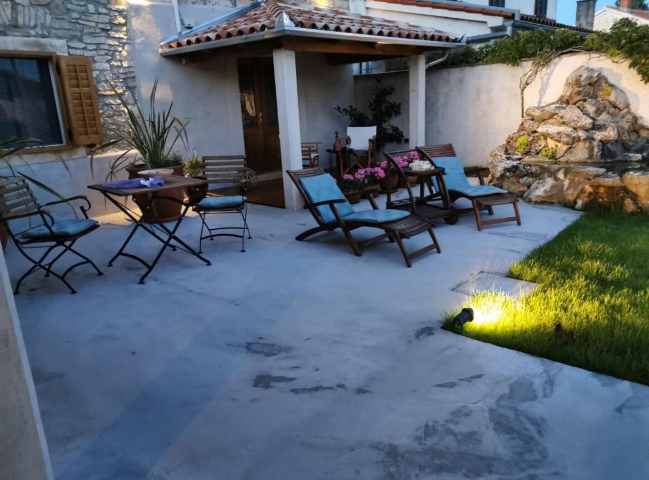 Een terras met tuinmeubilair, een stenen muur en een kleine tuin.