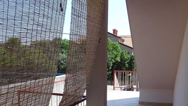 Un balcón con vista a una calle, una barandilla y un edificio al fondo.
