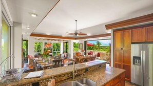 A modern kitchen with a central island, stainless steel appliances, and a view of a lush garden.