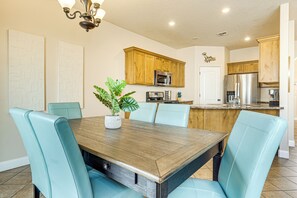 Un coin repas avec une table en bois et des chaises bleu clair, une plante en pot et des meubles en bois en arrière-plan.
