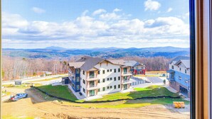 Un immeuble d’appartements moderne, doté de plusieurs étages, de balcons et offrant une vue sur les montagnes lointaines.