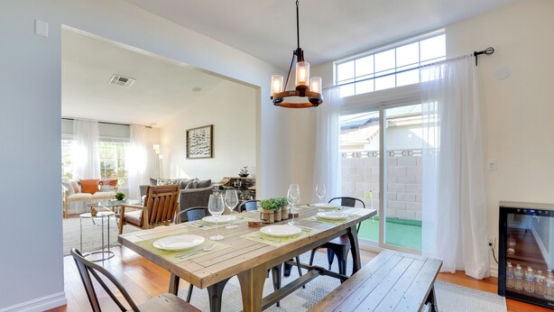 A dining area with a wooden table set for four, a bench, and a refrigerator. - Outdoor Oasis & Game Room: Henderson Retreat (Henderson)