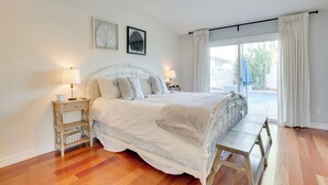 A bedroom with a bed, bedside tables, a bench, a ceiling fan, and a window with curtains. - Outdoor Oasis & Game Room: Henderson Retreat (Henderson)