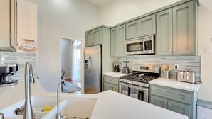 A modern kitchen with stainless steel appliances, light green cabinets, and a white countertop. - Outdoor Oasis & Game Room: Henderson Retreat (Henderson)