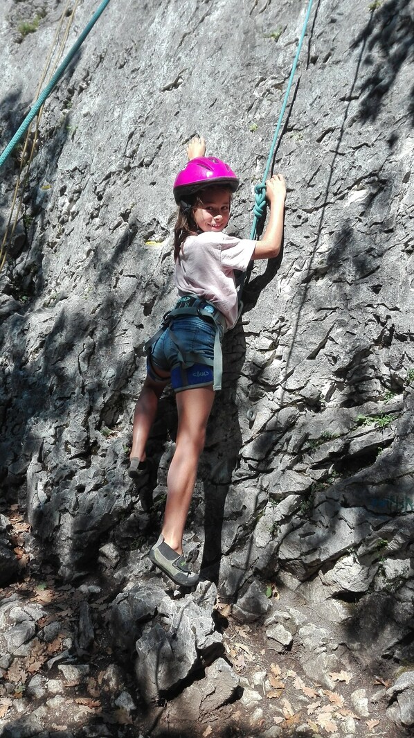 A person climbing a rocky surface with a helmet and harness. - La Grange (Chainaz-les-Frasses)