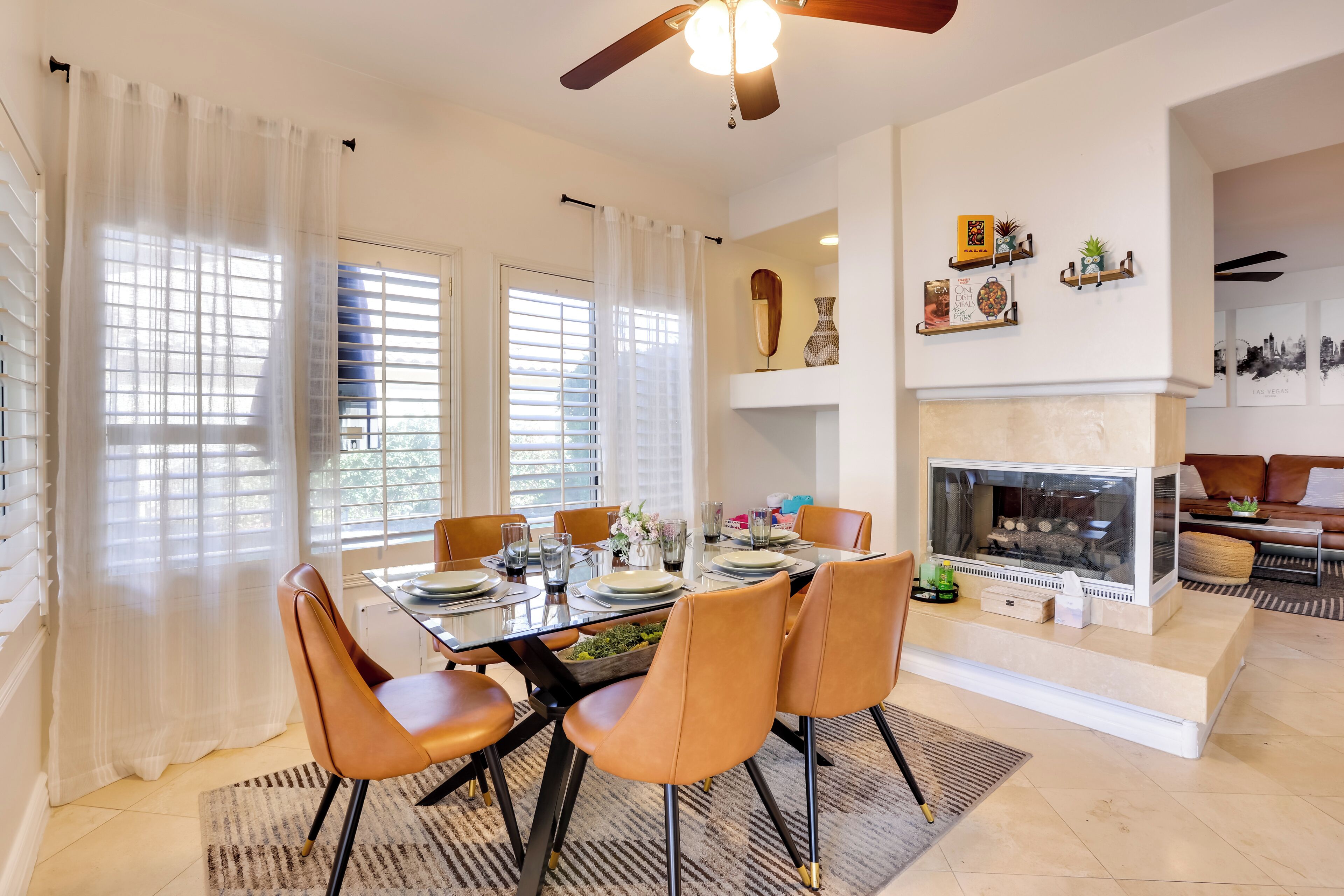 Un coin repas avec une table en verre, des chaises orange et une cheminée.