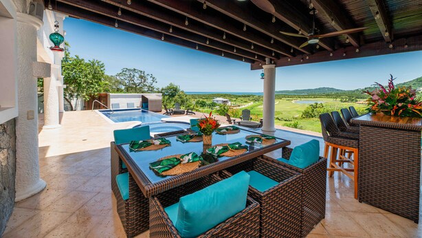 Eine Terrasss mit Pool, Korbmöbeln und Blick auf die Landschaft.