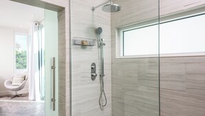 Une salle de bain moderne avec une douche à parois de verre, un porte-serviettes et une fenêtre.