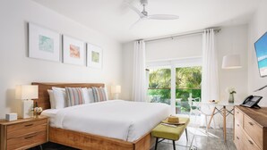 Une chambre moderne avec un lit en bois, des tables de chevet, un bureau et une vue sur la verdure.