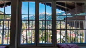 A room with large windows offering a view of a mountainous landscape and a town below. - Picturesque Apartment in Salzburg (Bad Gastein)