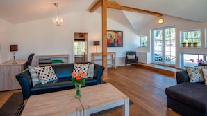 A spacious living room with a high ceiling, wooden beams, a chandelier, and large windows. - Picturesque Apartment in Salzburg (Bad Gastein)