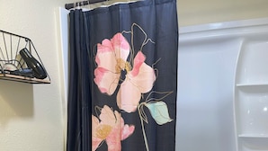 A bathroom with a toilet, a bathtub, and a shower curtain with floral designs.