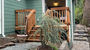 A house with a wooden front porch, a potted plant, and a small garden area.