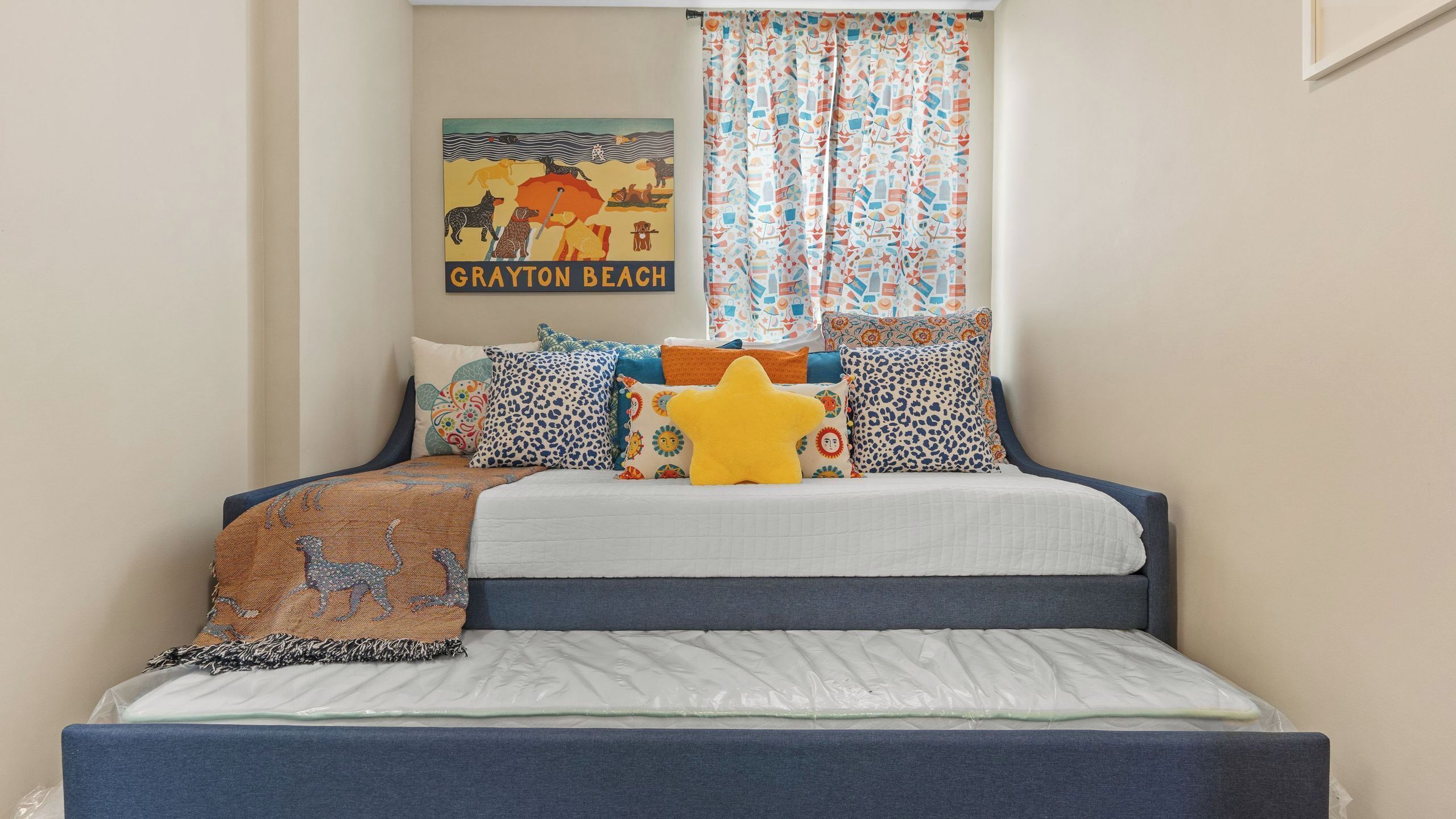 A bed with a headboard, multiple pillows, a blanket, and a wall poster.