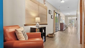 A hallway with a leather sofa, a bookshelf, a lamp, and a large abstract painting on the wall. - As You Like It by Avantstay Steps to Beach, Bikes, Sleeps 18! (Santa Rosa Beach)