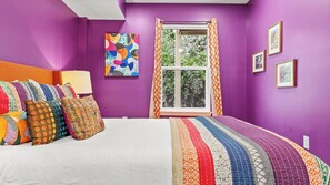 A bedroom with a bed, colorful pillows, a window with curtains, and wall art. - As You Like It by Avantstay Steps to Beach, Bikes, Sleeps 18! (Santa Rosa Beach)