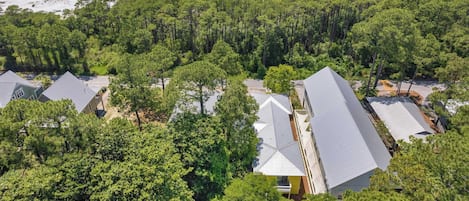 An aerial view of a resort with multiple buildings, surrounded by dense forest and a beach.