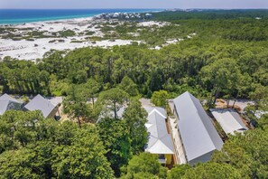 An aerial view of a resort with multiple buildings, surrounded by dense forest and a beach. - As You Like It by Avantstay Steps to Beach, Bikes, Sleeps 18! (Santa Rosa Beach)
