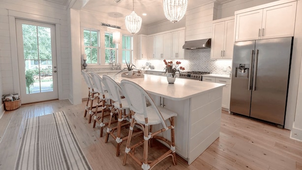 A spacious kitchen with a large island, white cabinetry, and stainless steel appliances.