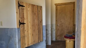 A hallway with a wooden wardrobe, a marble-tiled wall, and a tiled floor.