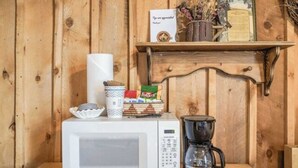 En mikrobølgeovn, kaffemaskine og en hylde med skilte samt dekorative genstande foran en trævæg.