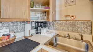 A kitchen with wooden cabinets, a stainless steel sink, and a decorative backsplash. - Prospector Cabin - Kitchen included (Lake George)