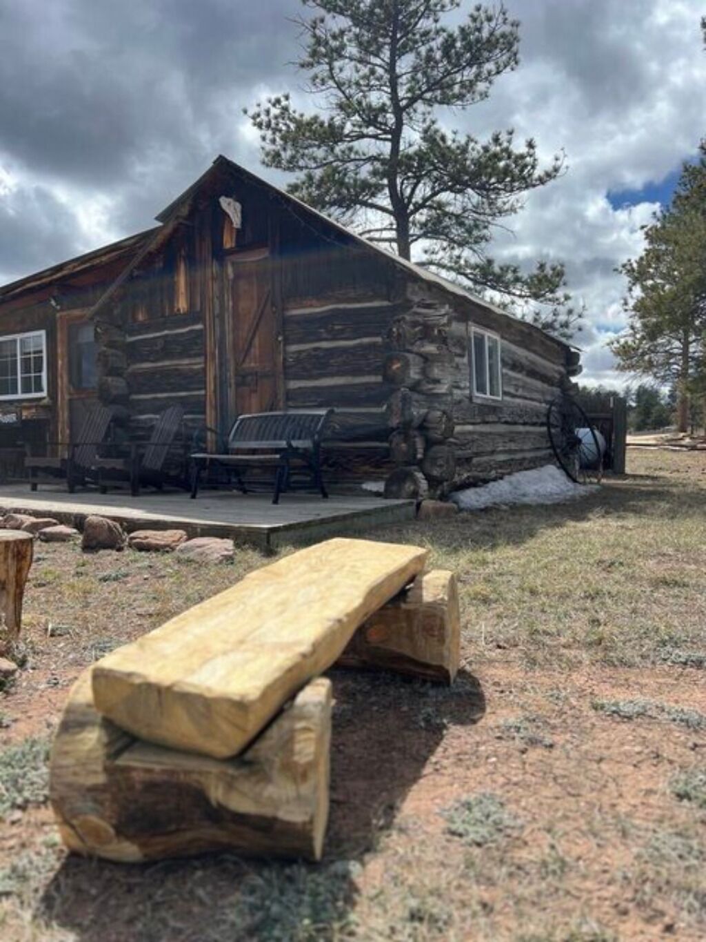 En rustik hytte med veranda og et picnicbord foran.