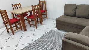 Un salon avec un canapé marron, une table à manger en bois avec des coussins rouges et un tapis à motifs.