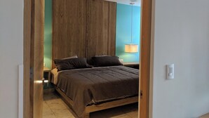 A bedroom with a wooden headboard, a bed with dark bedding, a ceiling fan, and a bedside lamp. - Amazing 2 floor penthouse w/PRIVATE rooftop (Playa del Carmen)