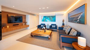 Een moderne woonkamer met een flatscreen televisie, twee banken, een salontafel en kunstwerken aan de muren.