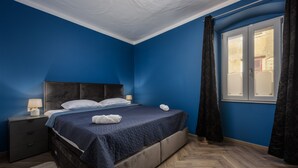 Een slaapkamer met een bed, nachtkastje en raam met gordijnen.