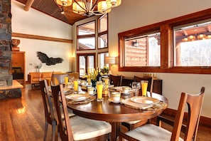 A dining area with a round table set for six, surrounded by wooden chairs.
