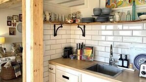 Cucina con piastrelle bianche stile metro, piano di lavoro in legno e rubinetto nero sospeso.