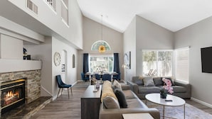 A spacious living room with a fireplace, a dining area, and a seating area with a sofa and chairs. - Modern 4BR Getaway w/ Pool (North Las Vegas)