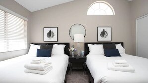 A hotel room with two beds, a nightstand, a mirror, and two framed pictures on the wall. - Modern 4BR Getaway w/ Pool (North Las Vegas)