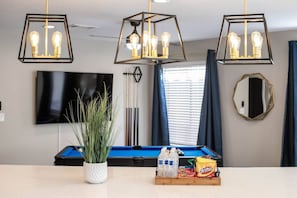 Uma mesa de bilhar com um vaso branco de plantas, água engarrafada e petiscos em cima de uma mesa.